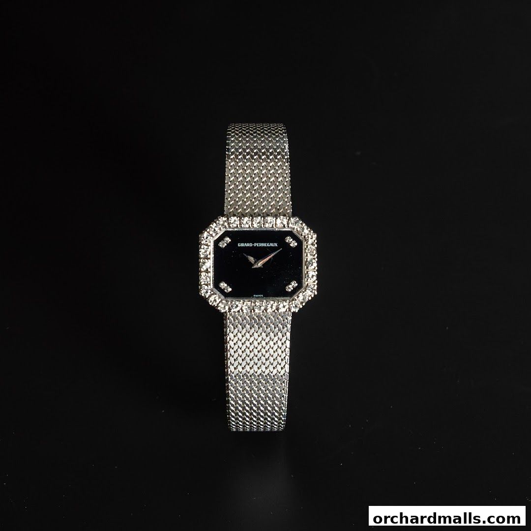 A luxurious Girard-Perregaux watch with a black dial and diamond bezel on a mesh bracelet.