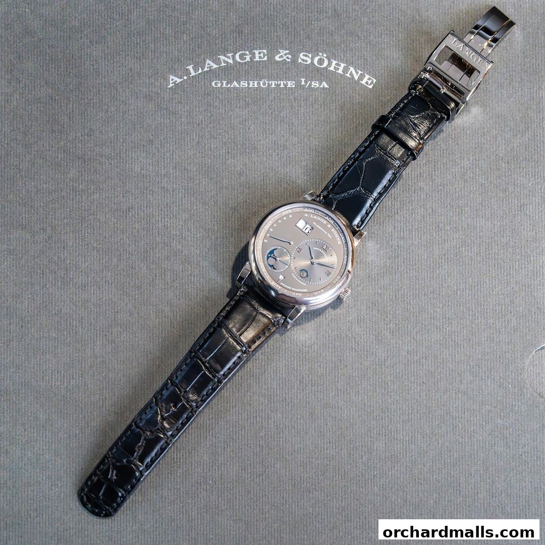 A luxurious A. Lange & Söhne watch with a black alligator strap on a textured grey background.
