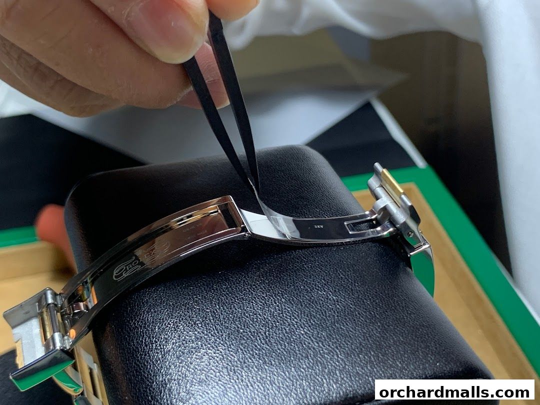 Close-up of a watch clasp being adjusted with tweezers, showcasing luxury craftsmanship.