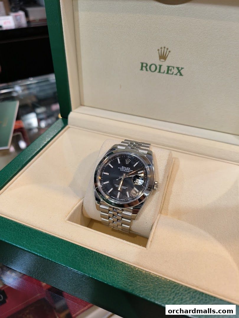 A luxury Rolex watch displayed in its original green and cream box.