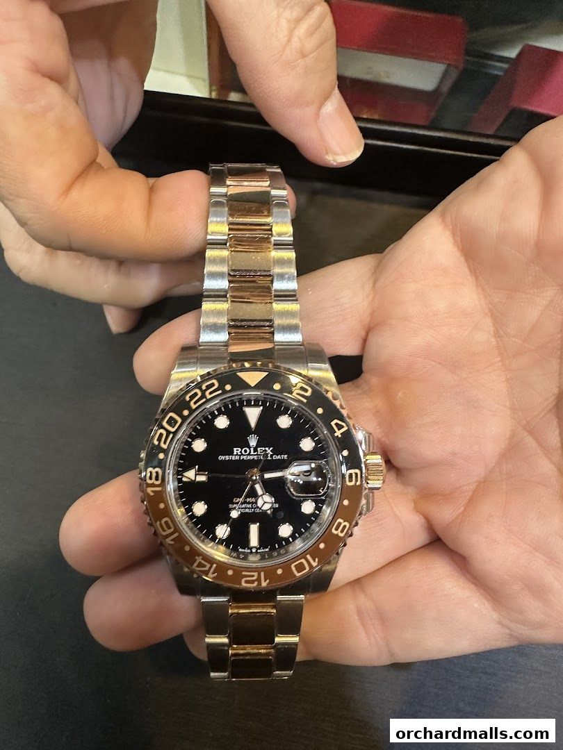 Hands holding a luxury Rolex watch with a two-tone metal band.