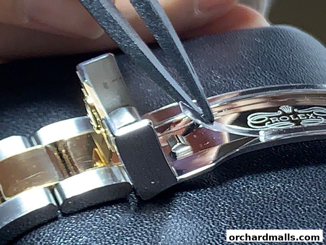 Close-up of a Rolex watch clasp being adjusted with tweezers.
