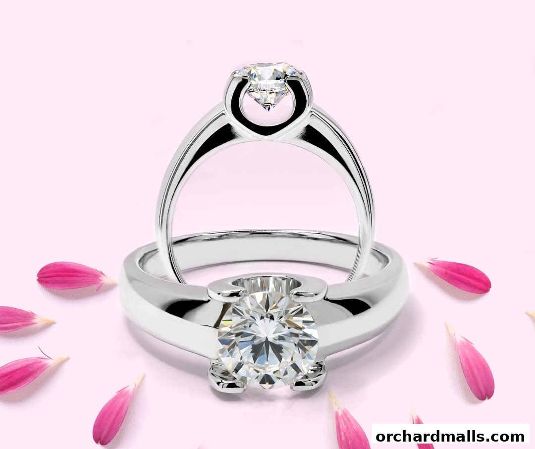 Two diamond rings are displayed with pink petals on a pink background.