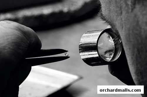 A jeweler inspects a small diamond with a loupe, showcasing precision and quality.