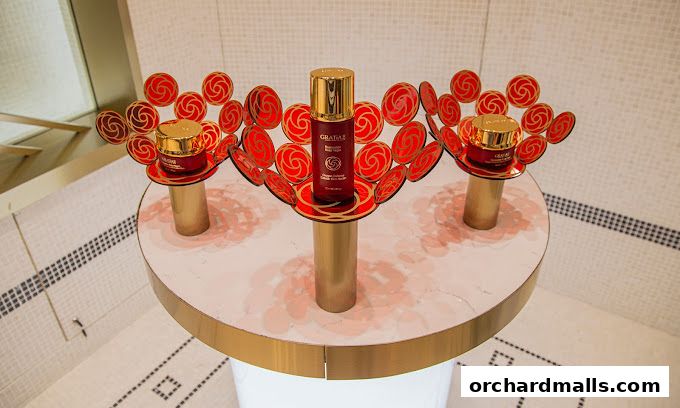 GRATiAE Takashimaya display featuring red and gold skincare products with floral accents.