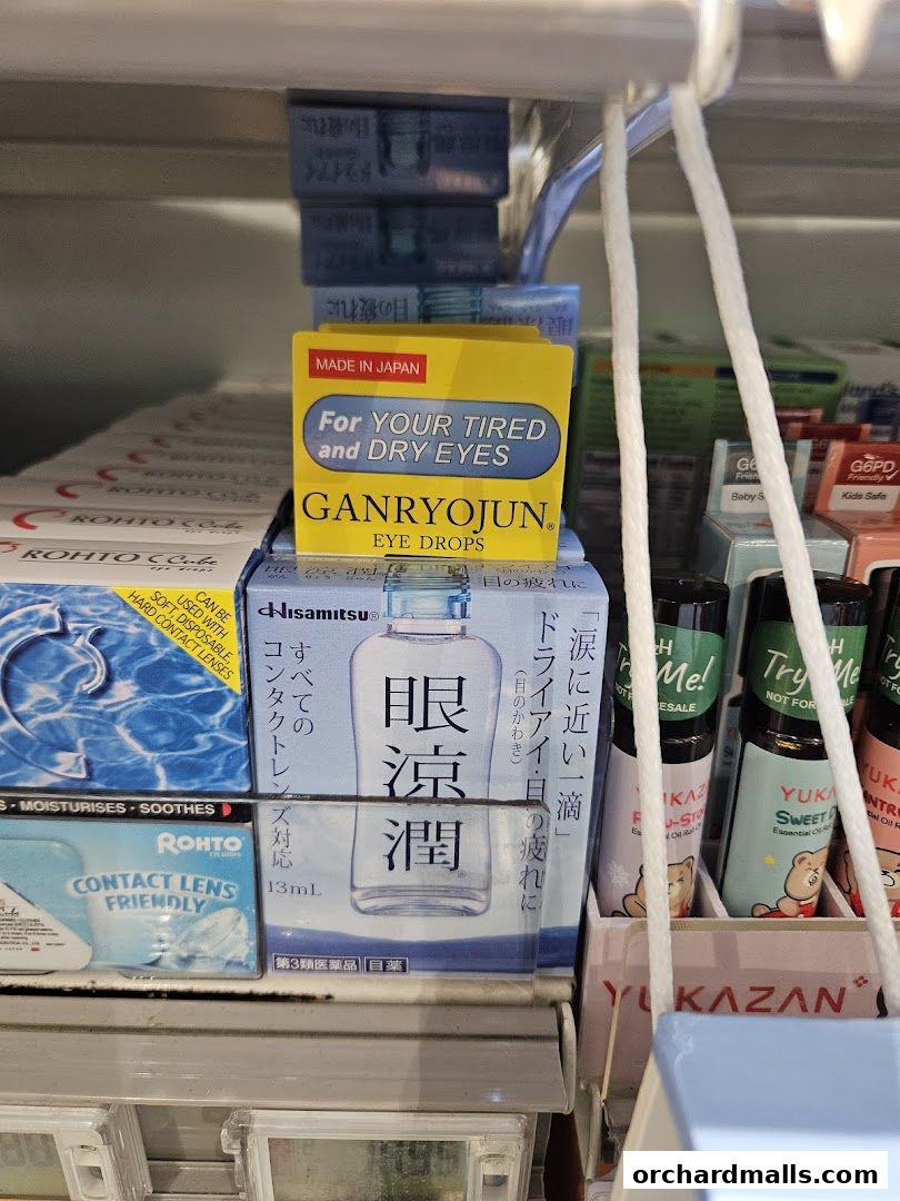 A shelf stocked with eye drops and contact lens solutions, featuring prominent brands like Ganryojun and Rohto.