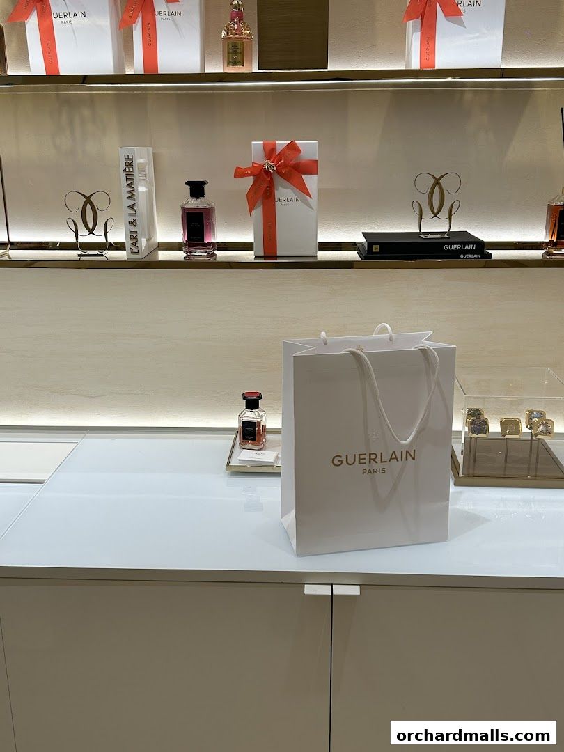 Guerlain boutique interior with perfumes, gift boxes, and shopping bags on display.
