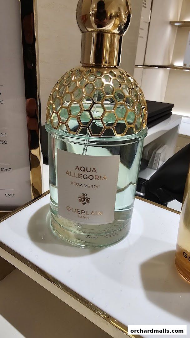 A close-up of a Guerlain Aqua Allegoria Rosa Verde perfume bottle with a honeycomb design.
