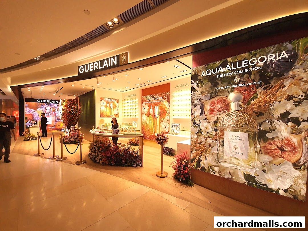 The Guerlain boutique entrance with displays of perfumes and floral arrangements.