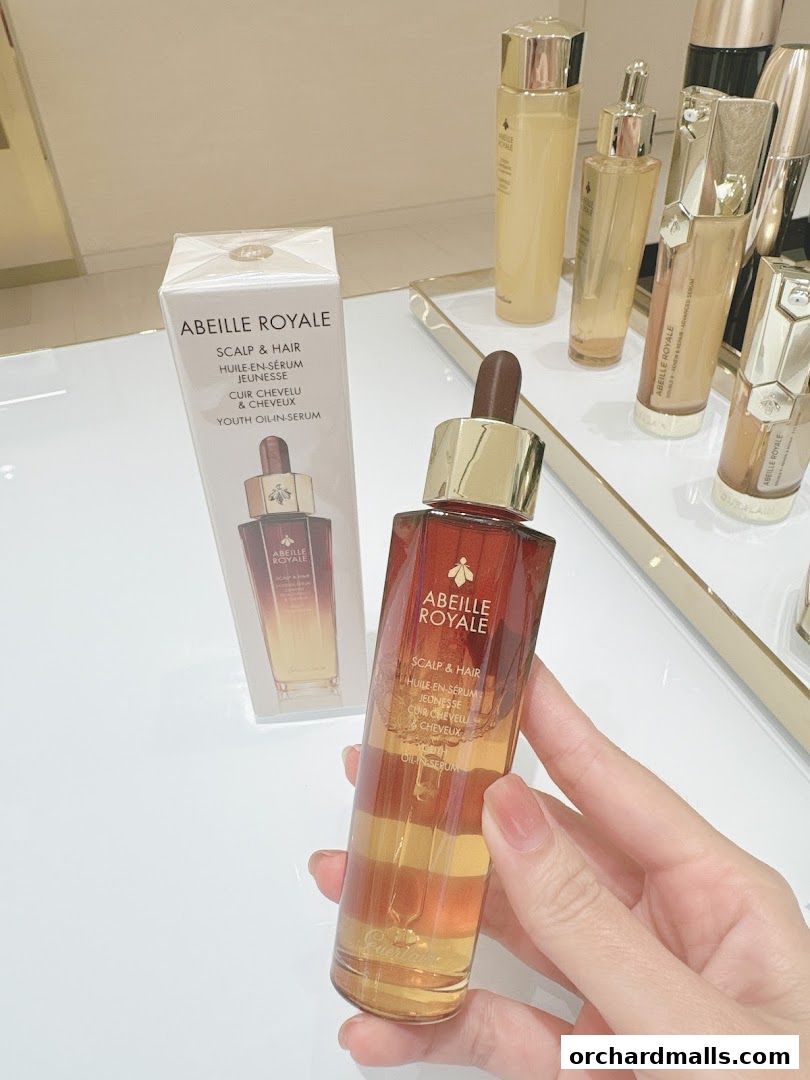 A hand holds a bottle of Guerlain Abeille Royale Youth Oil-in-Serum.