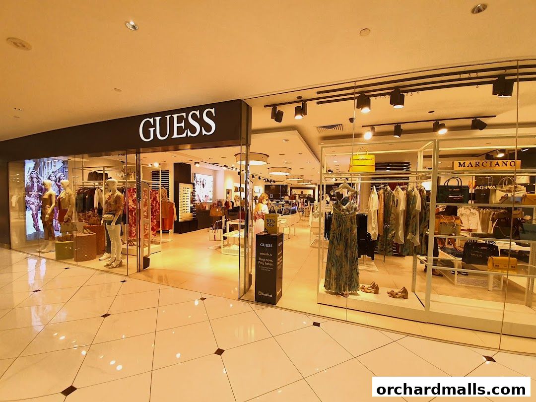 The GUESS store entrance displays mannequins in fashionable outfits and various accessories.