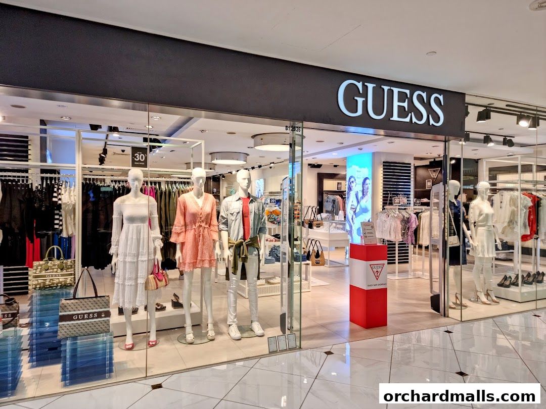 The GUESS store front displays mannequins in stylish outfits and branded bags.