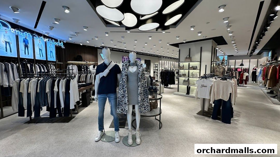 Interior view of a GUESS store showcasing apparel and accessories on mannequins and racks.