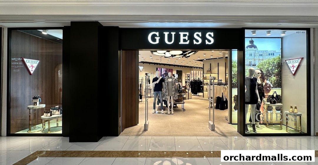 The entrance of a GUESS store, showcasing clothing and accessories on mannequins and displays.