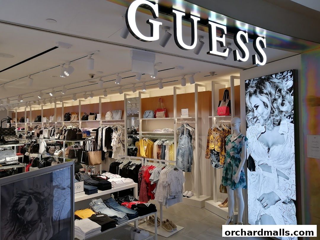 Interior view of a GUESS store showcasing handbags, apparel, and mannequins.