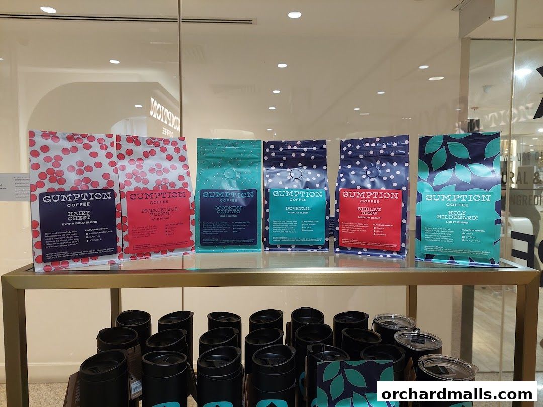 Bags of Gumption Coffee beans and travel mugs displayed on a shelf.