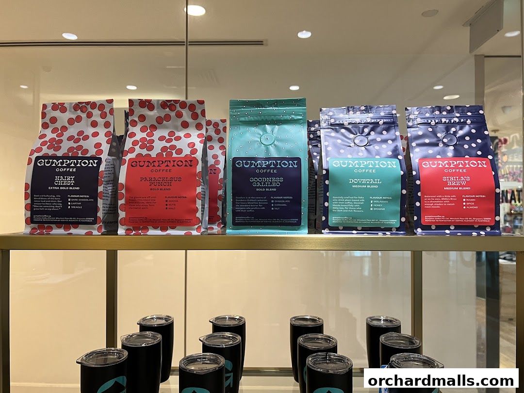 Bags of Gumption Coffee beans and travel mugs displayed on shelves.