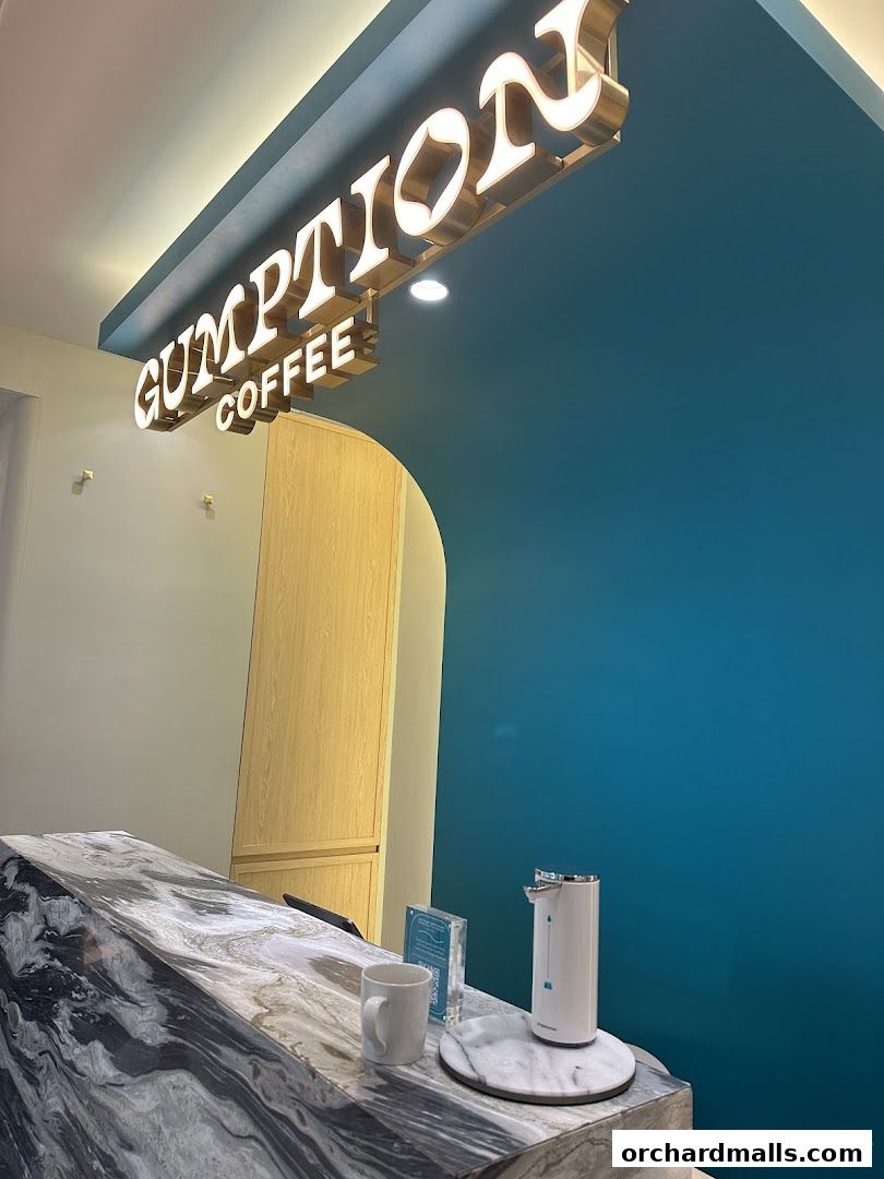 A coffee shop counter with a marble countertop and a prominent 'Gumption Coffee' sign.