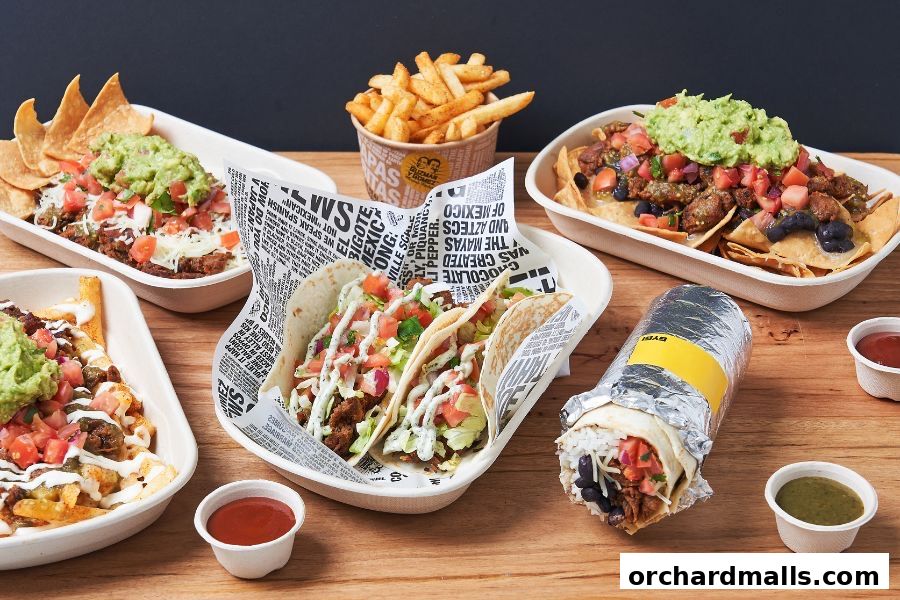 A spread of Mexican food including tacos, nachos, fries, and a burrito.
