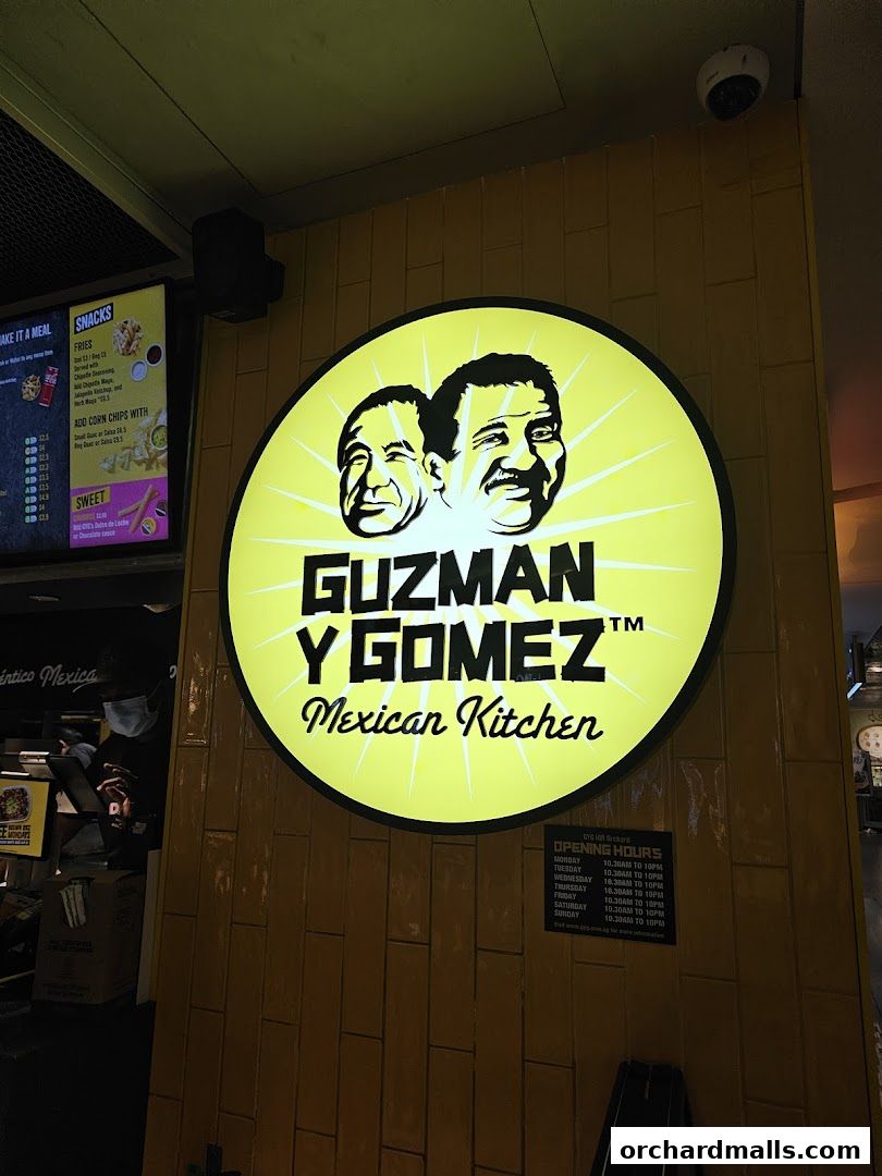 Guzman y Gomez Mexican Kitchen storefront with a large illuminated sign and menu board.