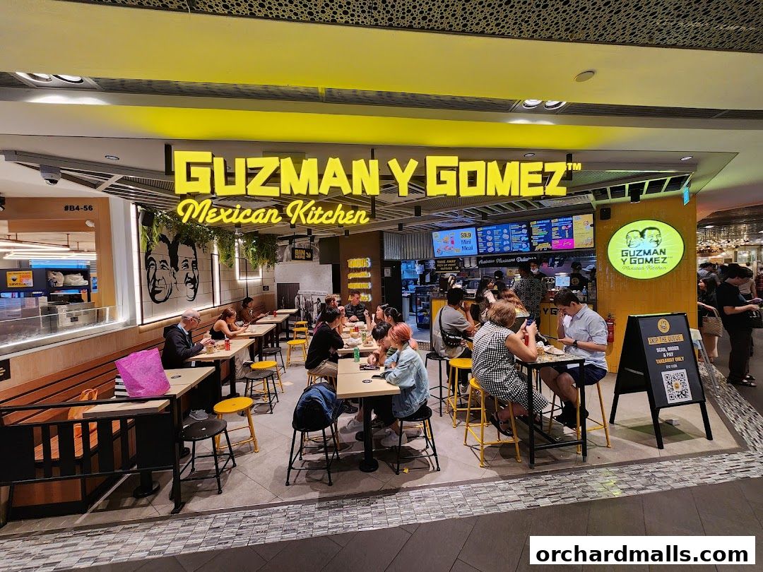 Guzman y Gomez Mexican Kitchen restaurant with customers dining inside and a prominent sign.
