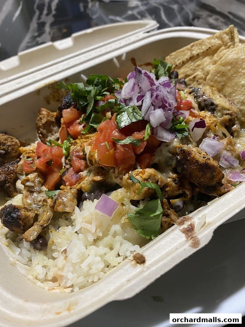 A delicious Guzman y Gomez burrito bowl with rice, beans, chicken, salsa, and chips.