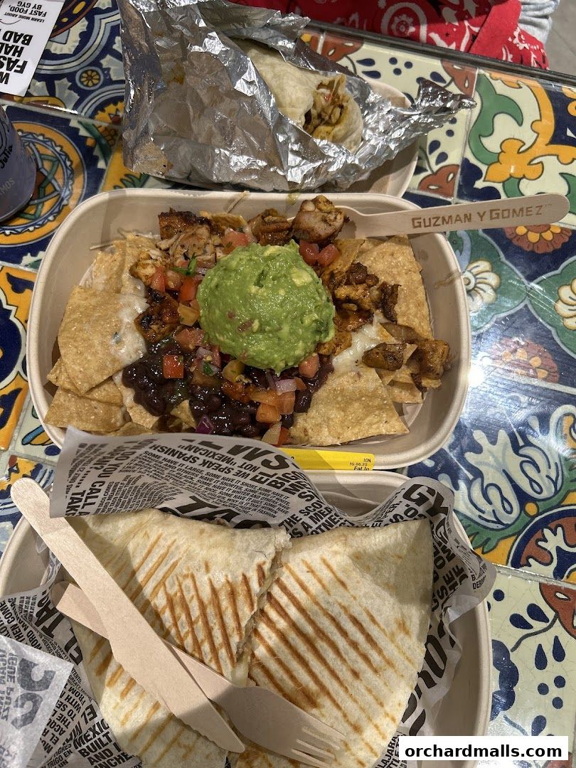 A close-up of Mexican food from Guzman y Gomez, including nachos, a burrito, and quesadillas.