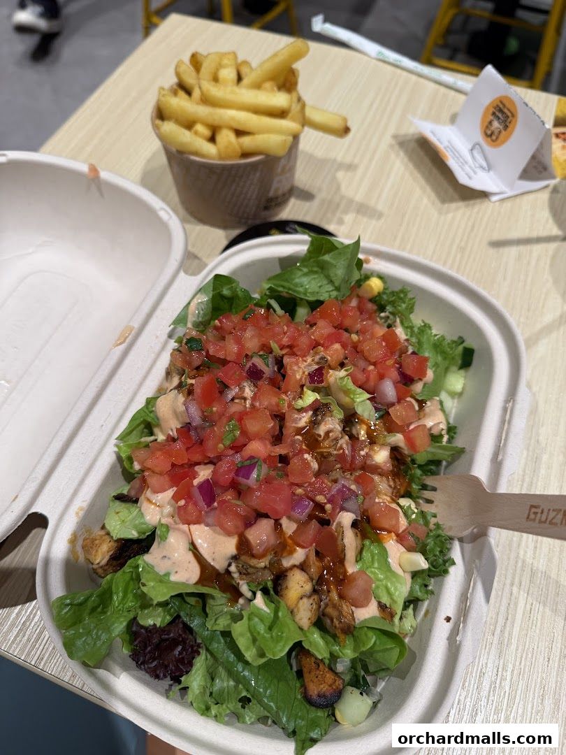 A fresh salad with chicken and salsa, served with a side of fries.