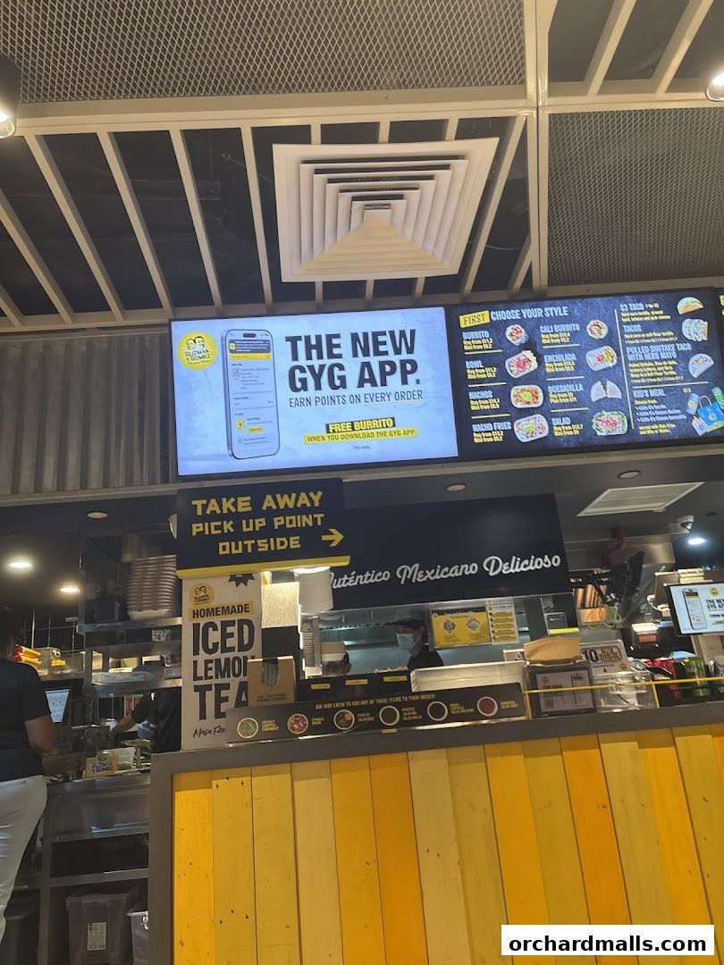 A Guzman y Gomez restaurant interior with a digital menu board and counter.