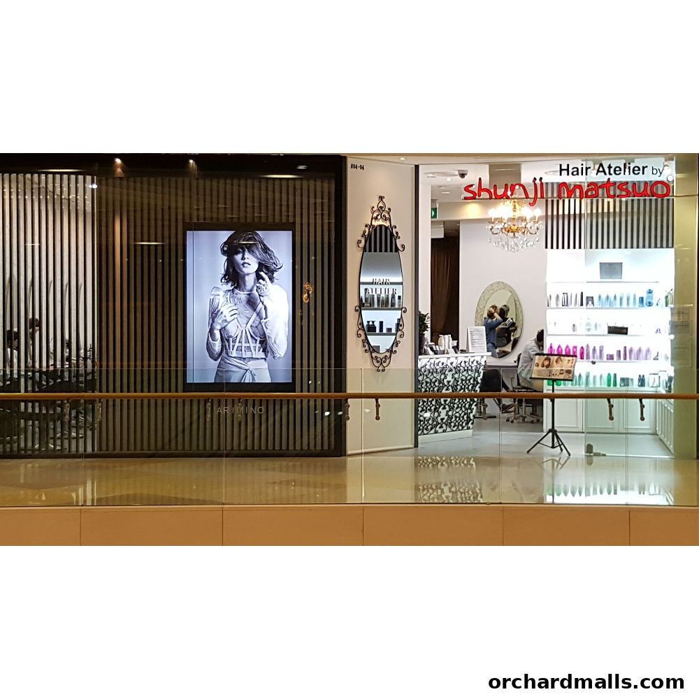 Exterior view of Hair Atelier by Shunji Matsuo, showcasing a stylish salon interior and a fashion advertisement.