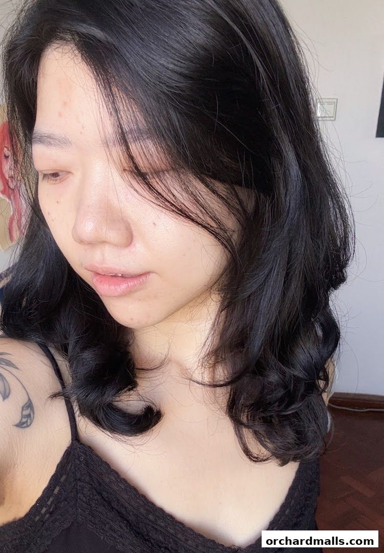 A close-up portrait of a woman with dark, wavy hair and fair skin.