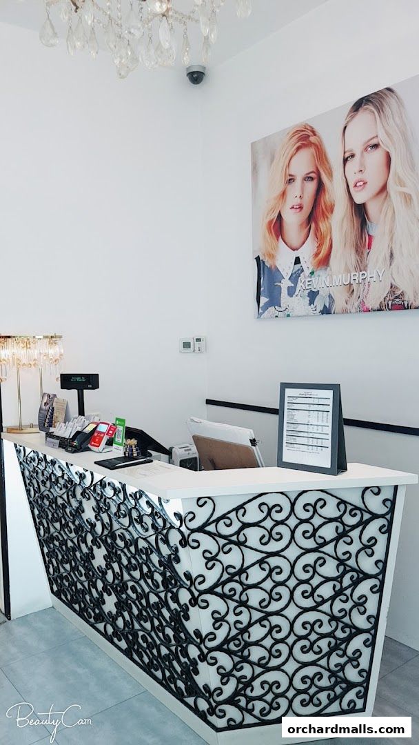 A reception desk at a hair salon with a decorative front and a poster of two models.