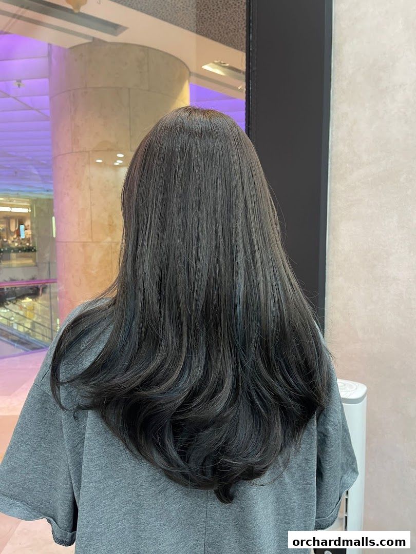 A person with long, dark, layered hair styled with soft waves.