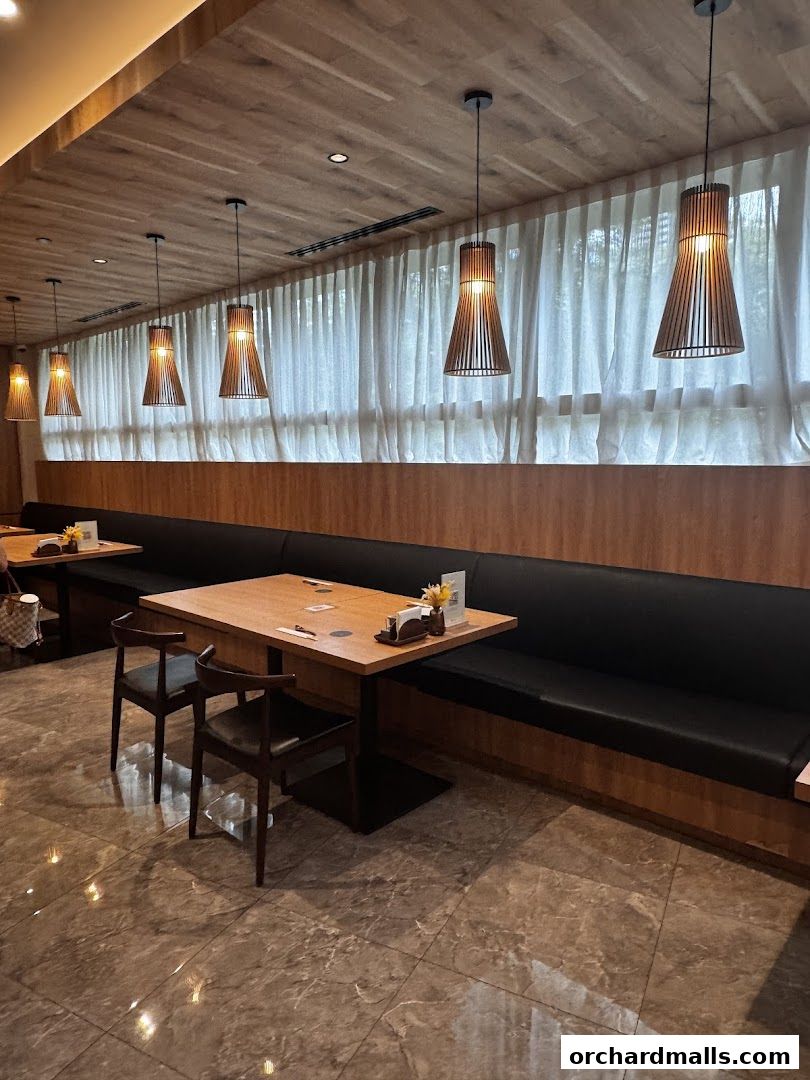 Interior of a restaurant with wooden accents, pendant lights, and booth seating.