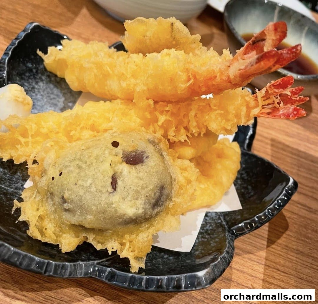 A close-up of a delicious plate of tempura, featuring shrimp and a vegetable.