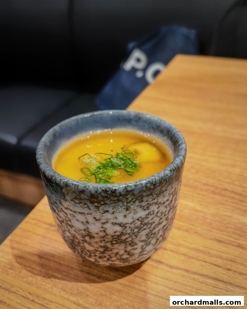 A close-up of a small bowl of savory custard topped with green onions.