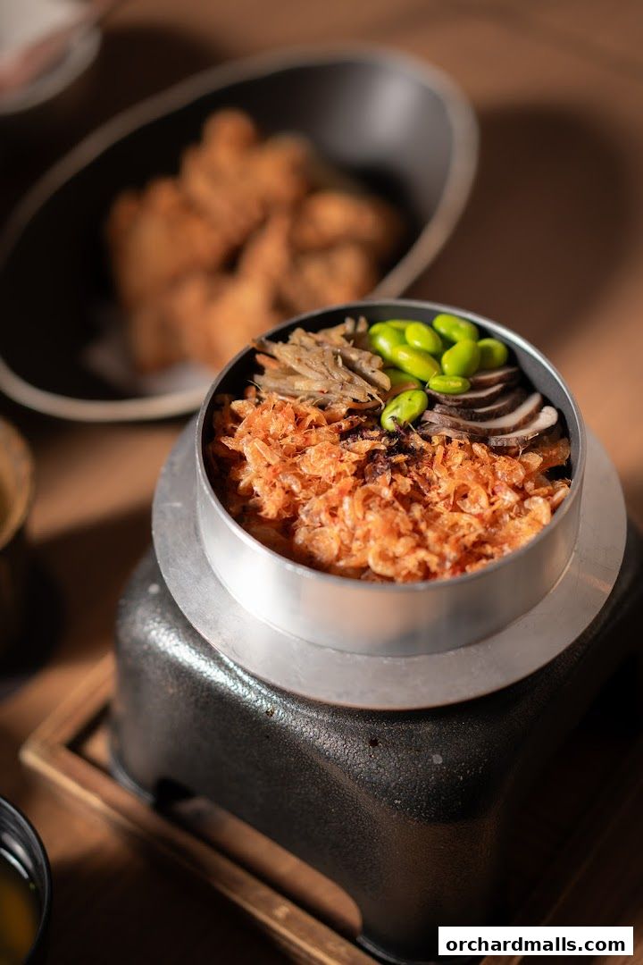 A close-up of a Japanese rice dish with shrimp, edamame, and mushrooms.