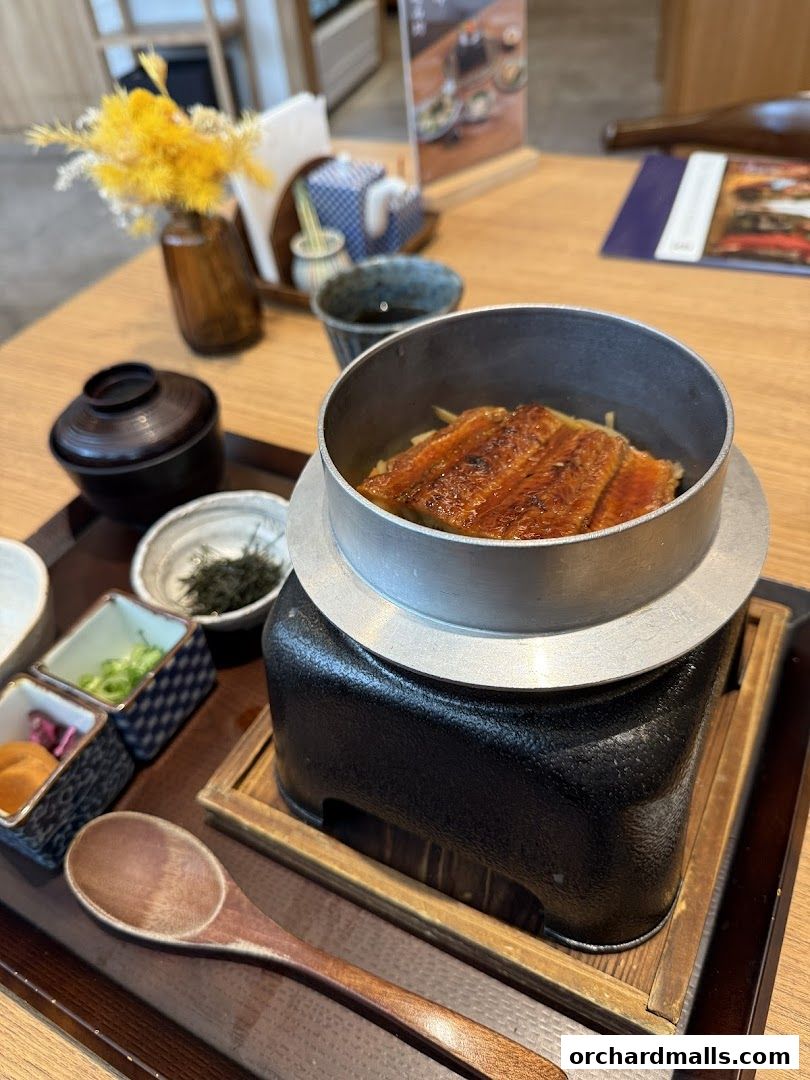 A delicious unagi donburi served in a traditional Japanese pot with side dishes.