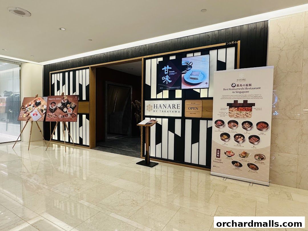 The entrance of Hanare by Takayama, a Japanese restaurant, with display boards and a promotional banner.