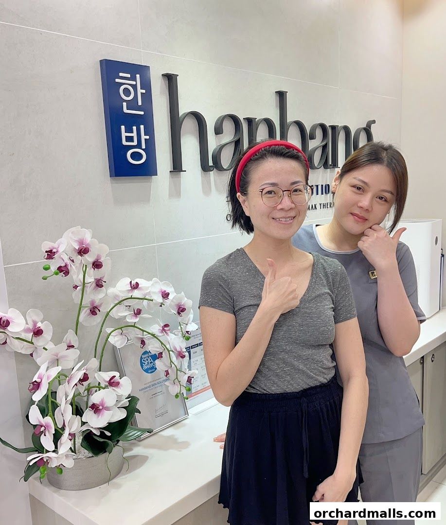 Two women smiling and giving thumbs up in front of Hanbang Skin Solutions.