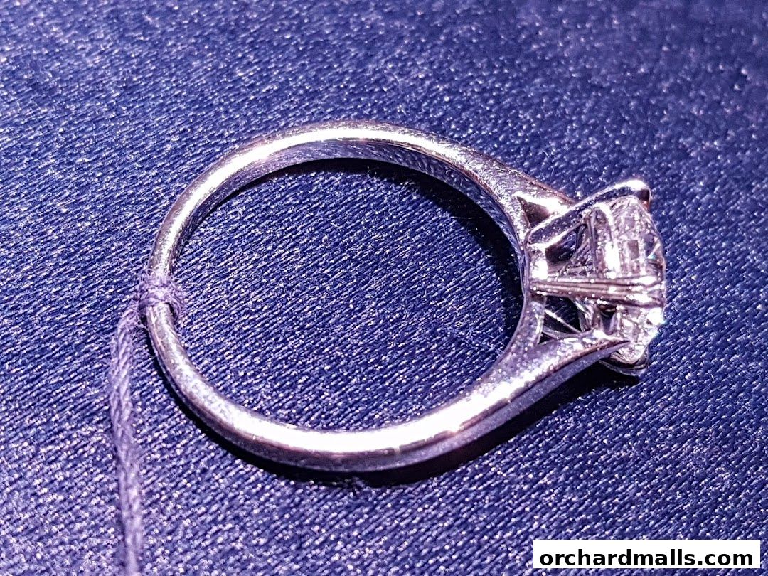 A close-up shot of a sparkling diamond engagement ring on a blue textured surface.