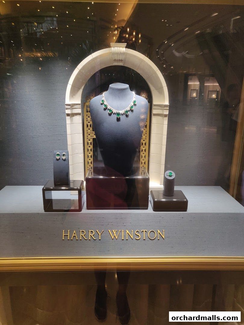 A Harry Winston jewelry display featuring a diamond and emerald necklace, earrings, and ring.