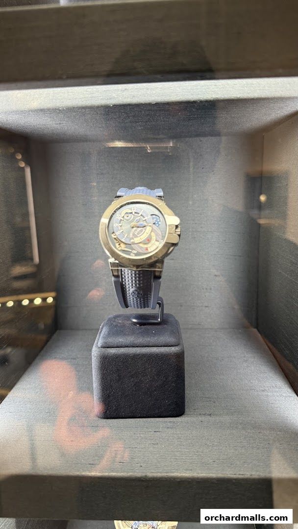A luxury watch with a gold case and black strap displayed in a glass case.