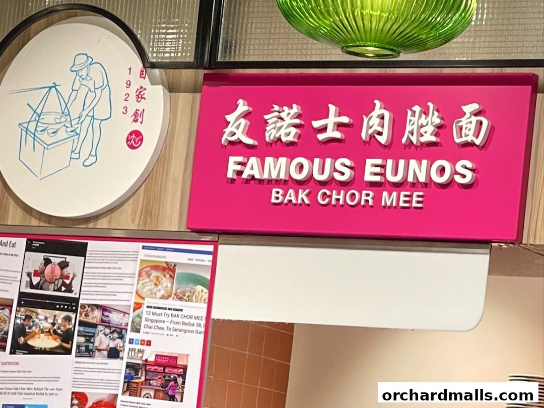 A sign for Famous Eunos Bak Chor Mee with a circular logo and a newspaper clipping.