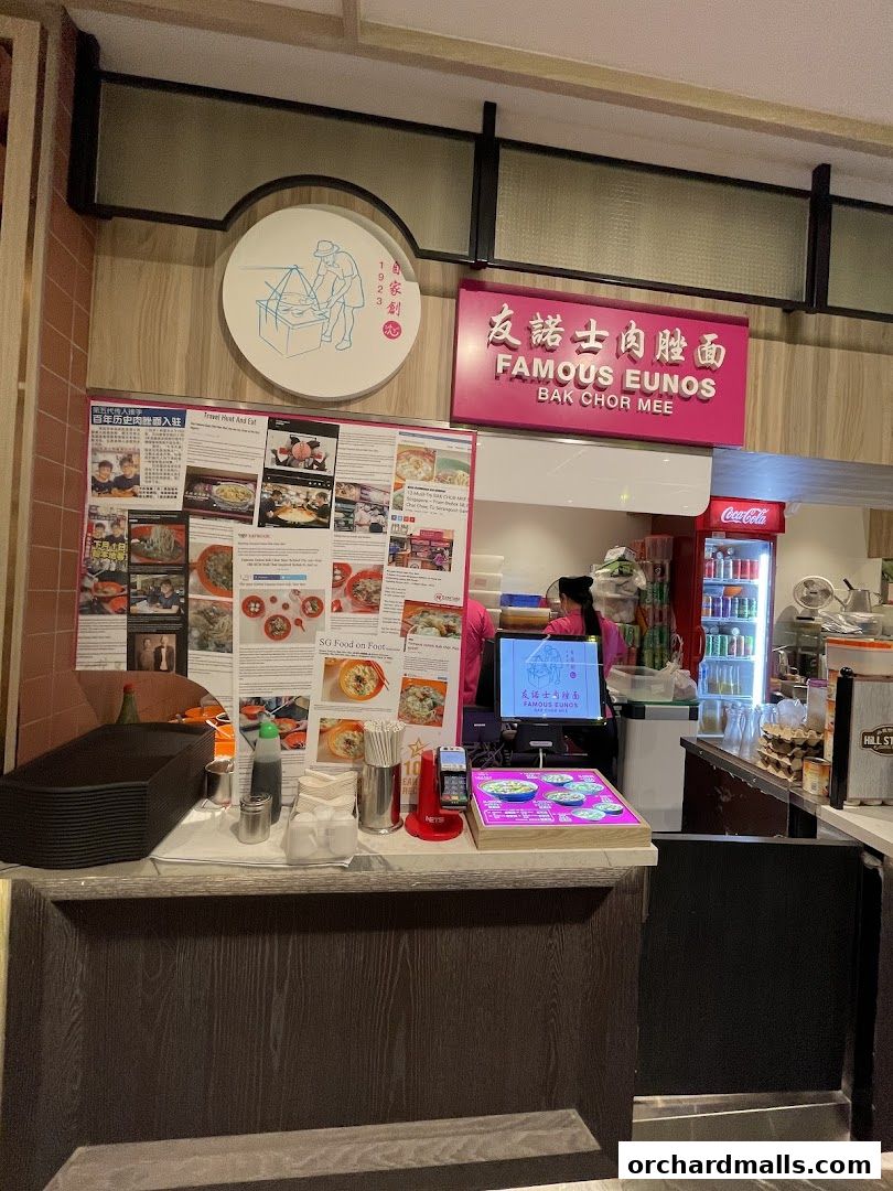 A food stall counter with a menu, ordering screen, and drinks cooler.