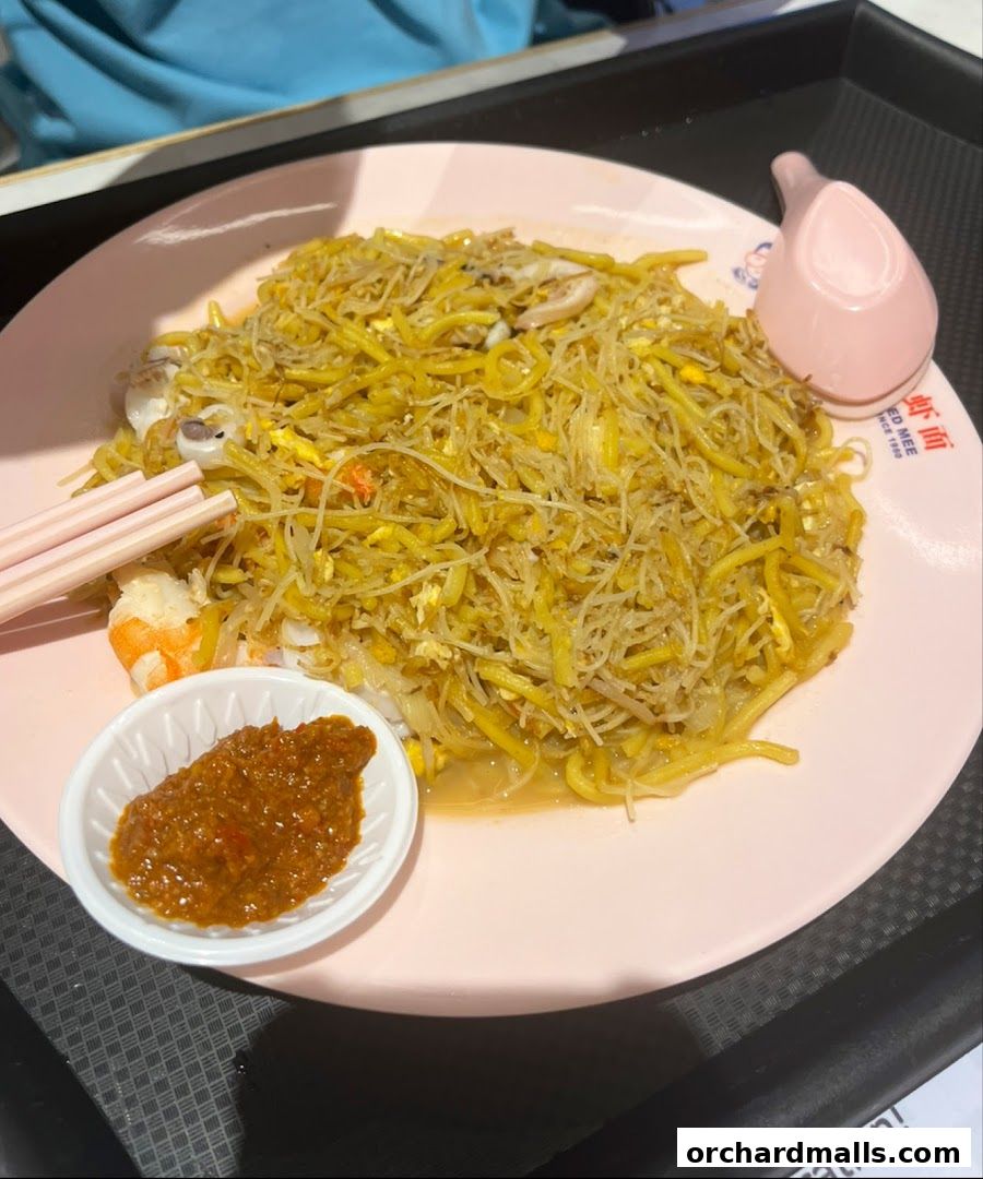 A plate of stir-fried noodles with shrimp, squid, and chili paste.