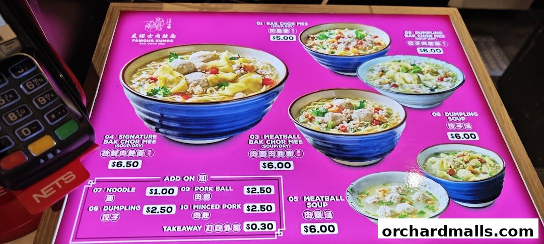 A brightly lit menu board displaying various noodle and soup dishes with prices.