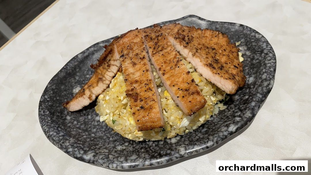 A plate of sliced grilled pork chops served over fried rice.