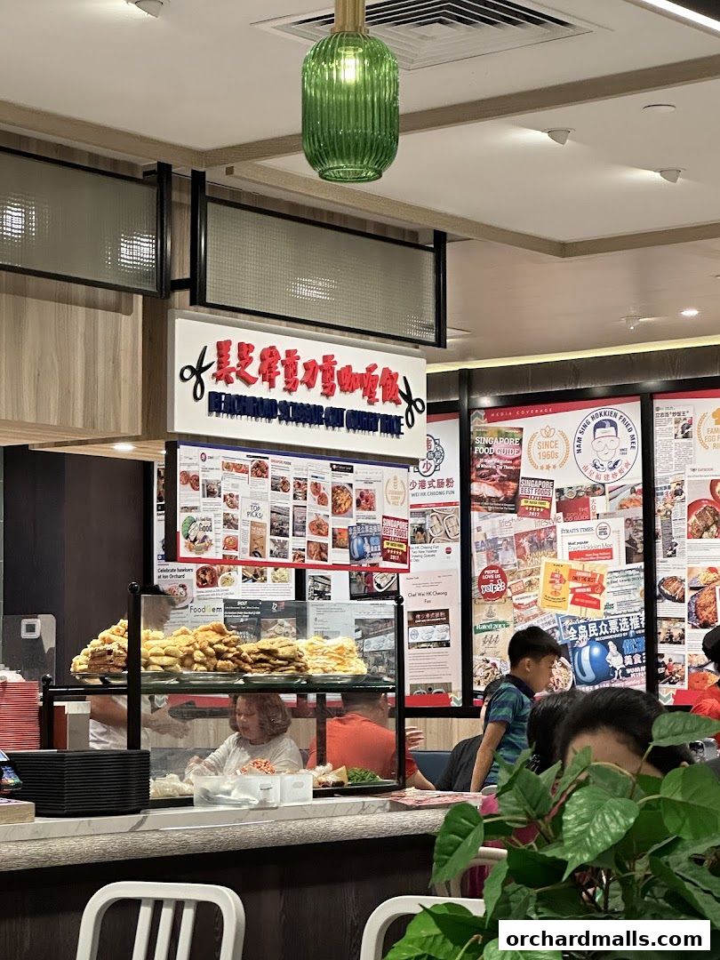 Interior view of a busy food stall with a display of fried food and customers.