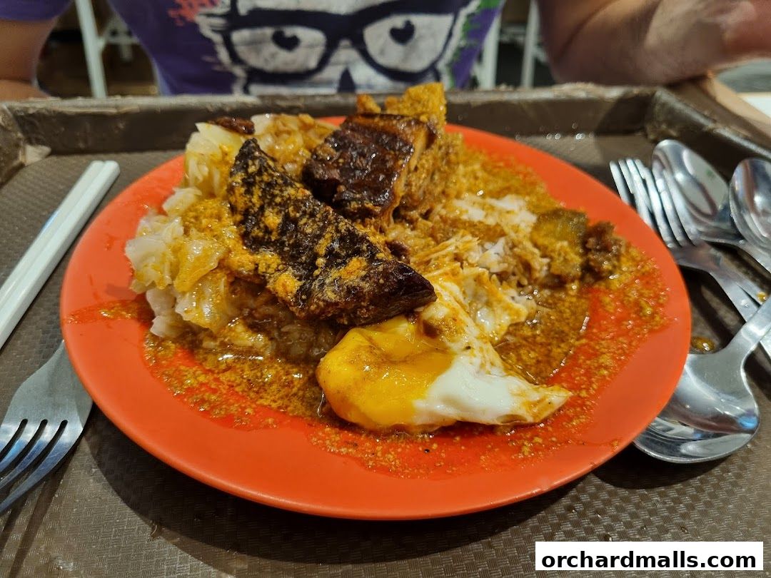 A plate of rice with meat, egg, and curry sauce, served with cutlery.